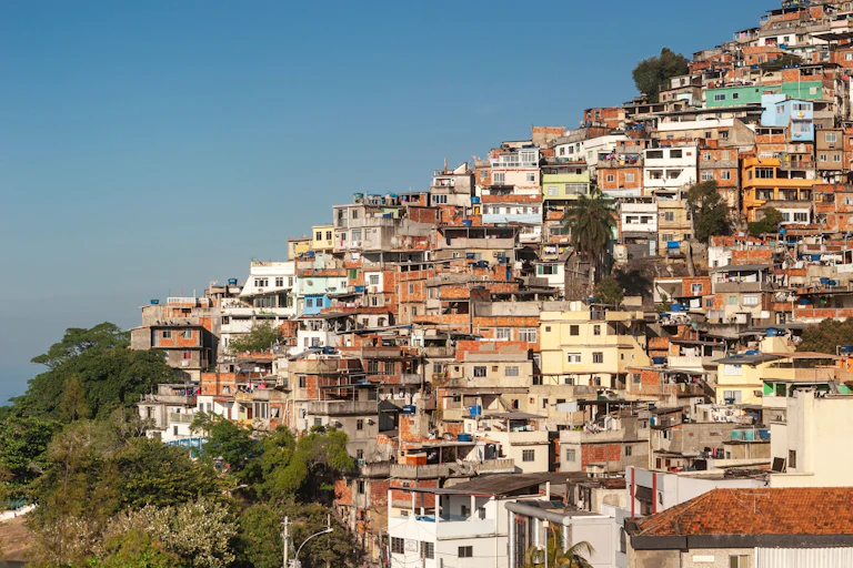 Casas de favela em uma encosta, sem áreas verdes sob um céu azul