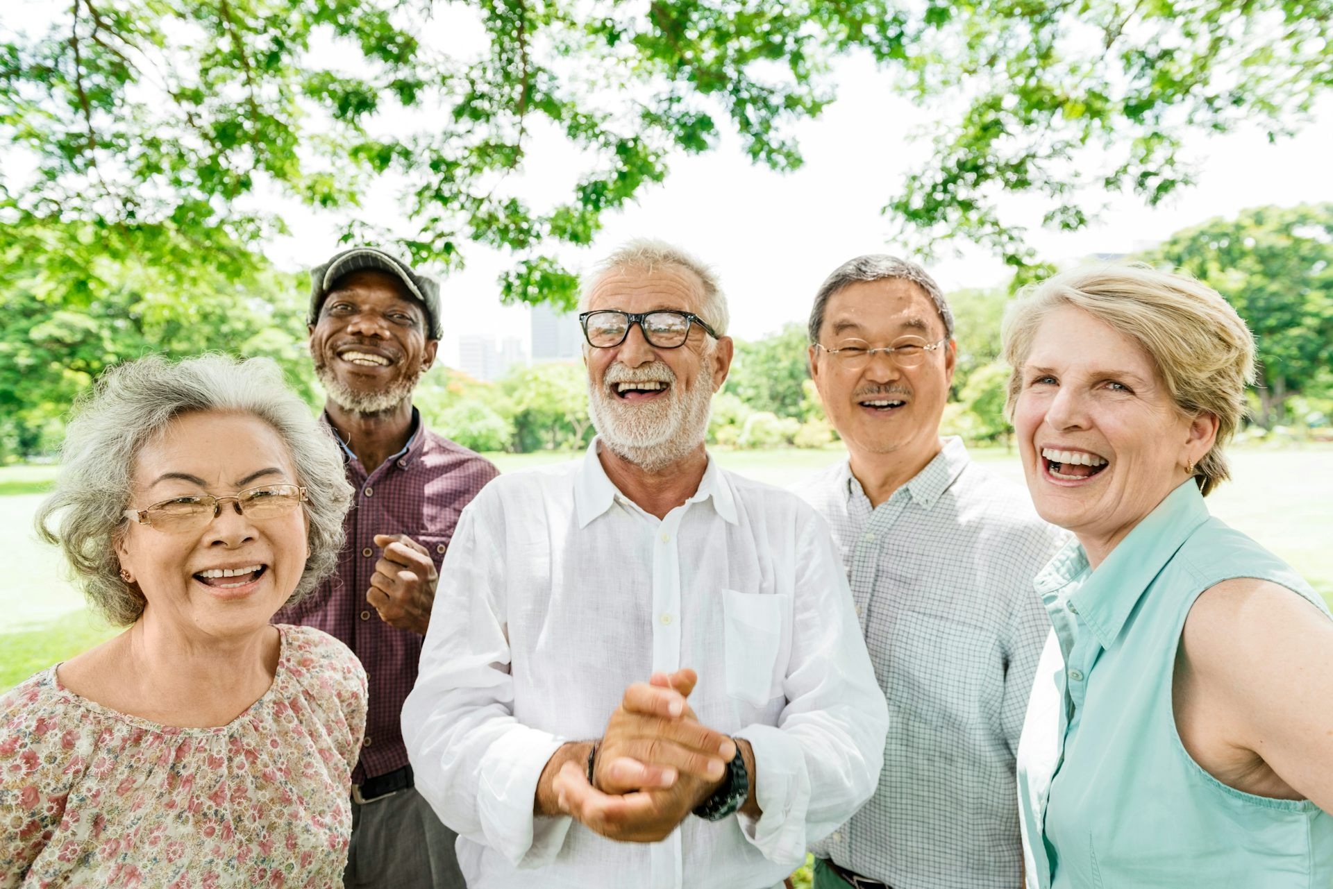 Five older adults smiling in an outdoor setting