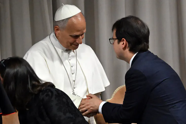 The pope shaking hands with a man in a suit