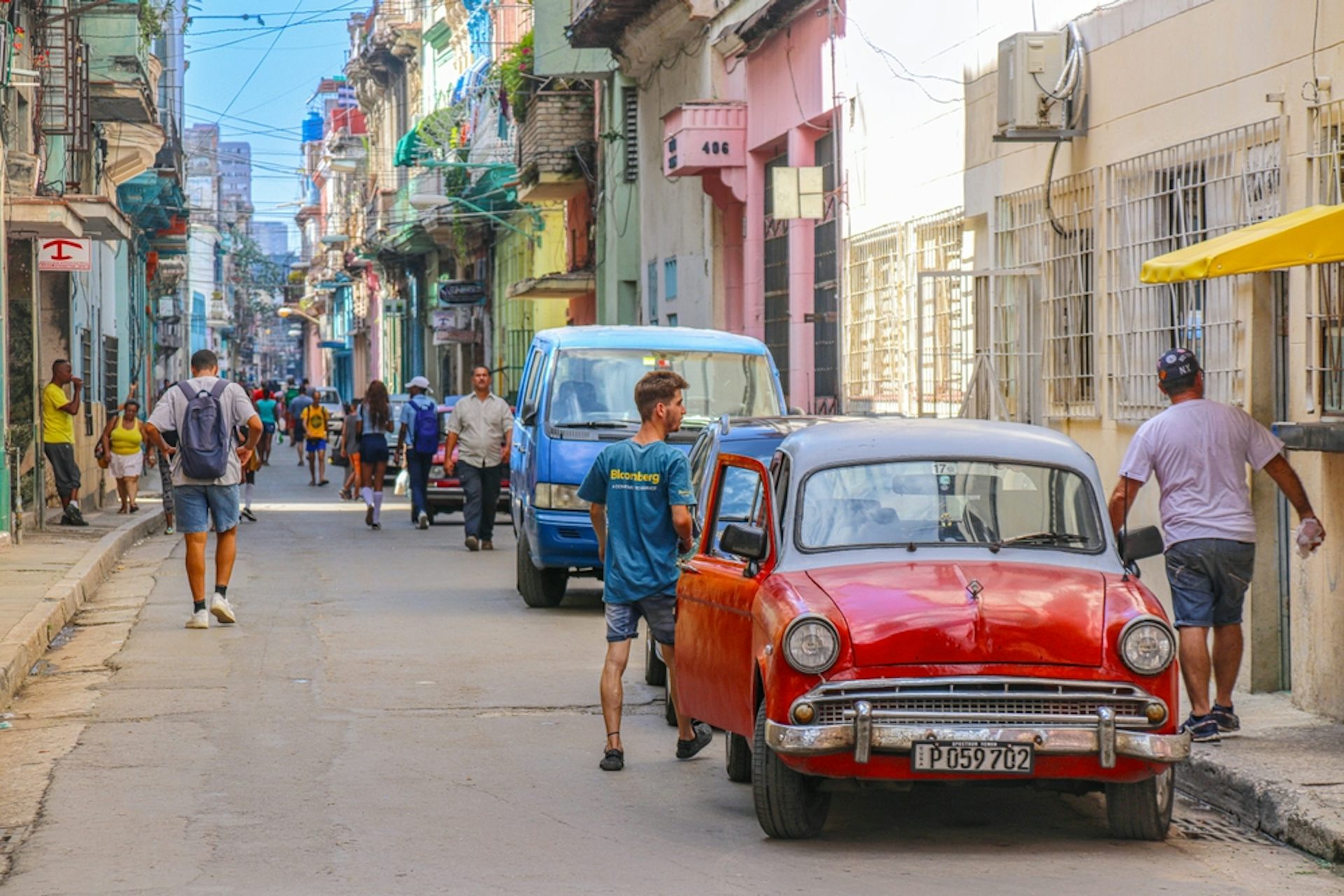 Escena callejera, con peatones y coches antiguos.
