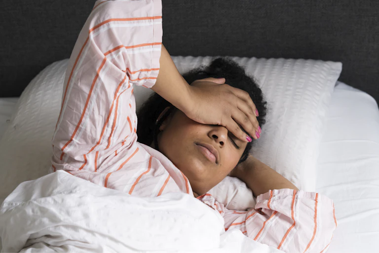 Women covers her face, feeling tired after waking up