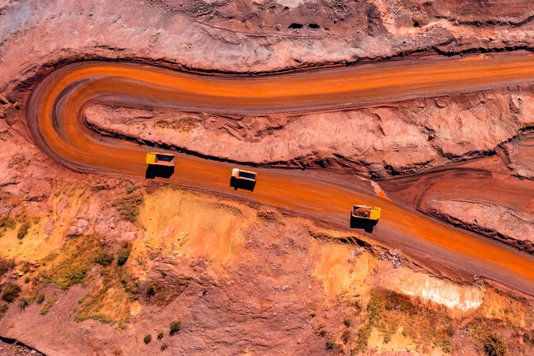Aerial view of trucks on a red dirt minesite road