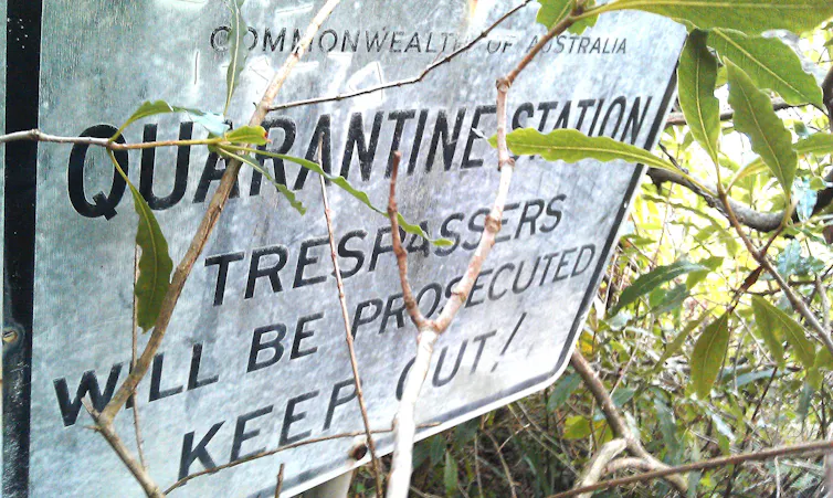 Overgrown sign for North Head Quarantine Station telling trespassers to keep out.