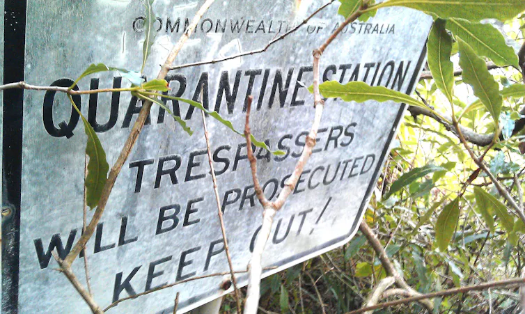 Overgrown sign for North Head Quarantine Station telling trespassers to keep out.