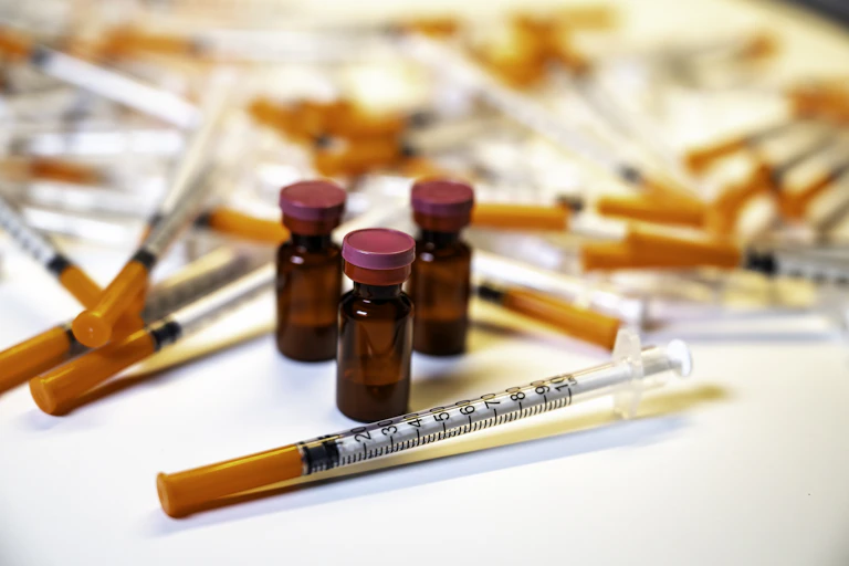 Three vials, which around surrounded by dozens of needles.