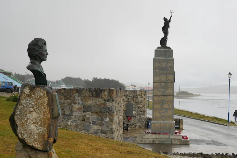 A bust of Margaret Thatcher looks across at a memorial to British troops in the Falklands Islands.