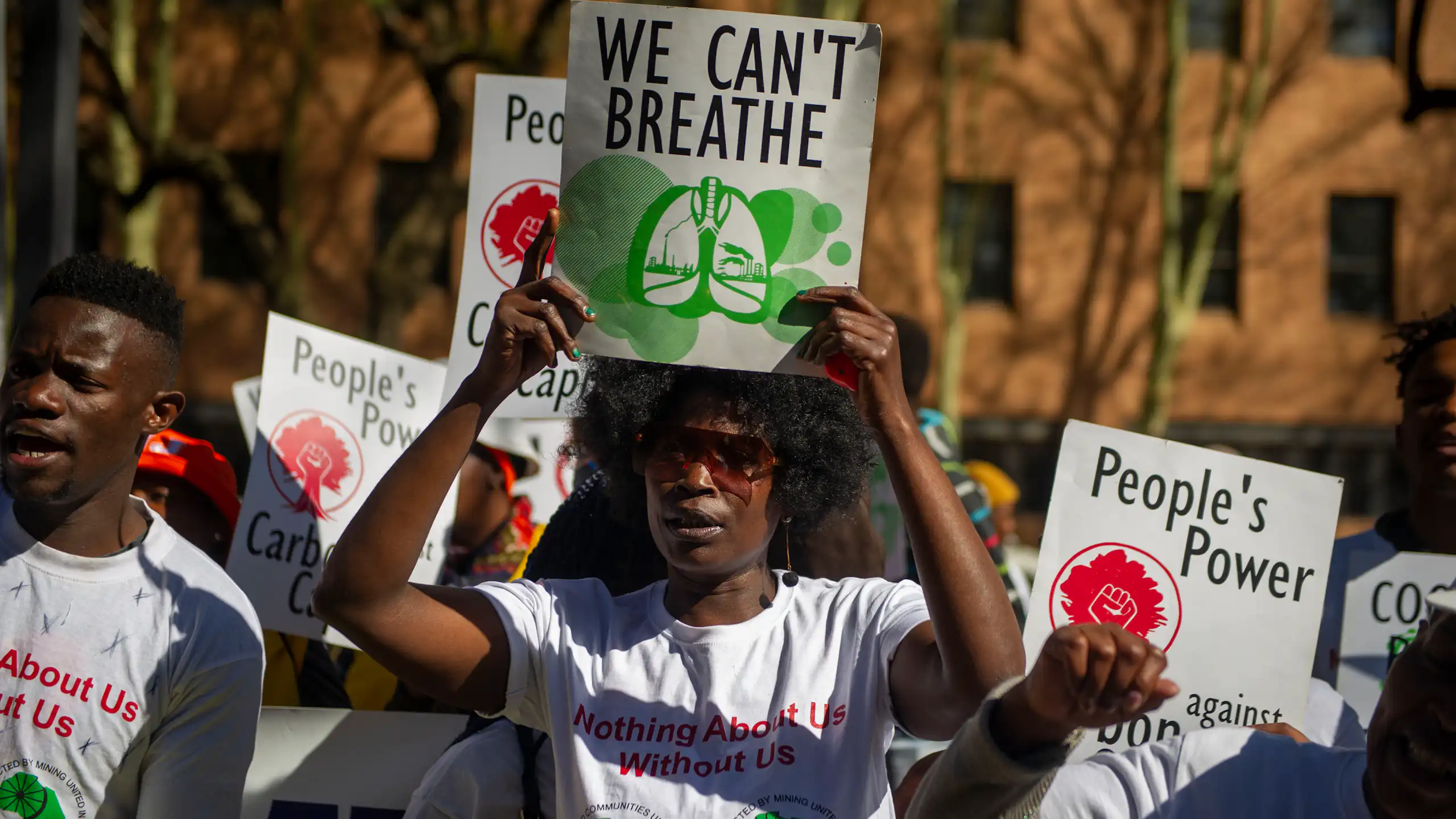 Students hold up signs saying 'People's power' and 'We Can't Breathe'