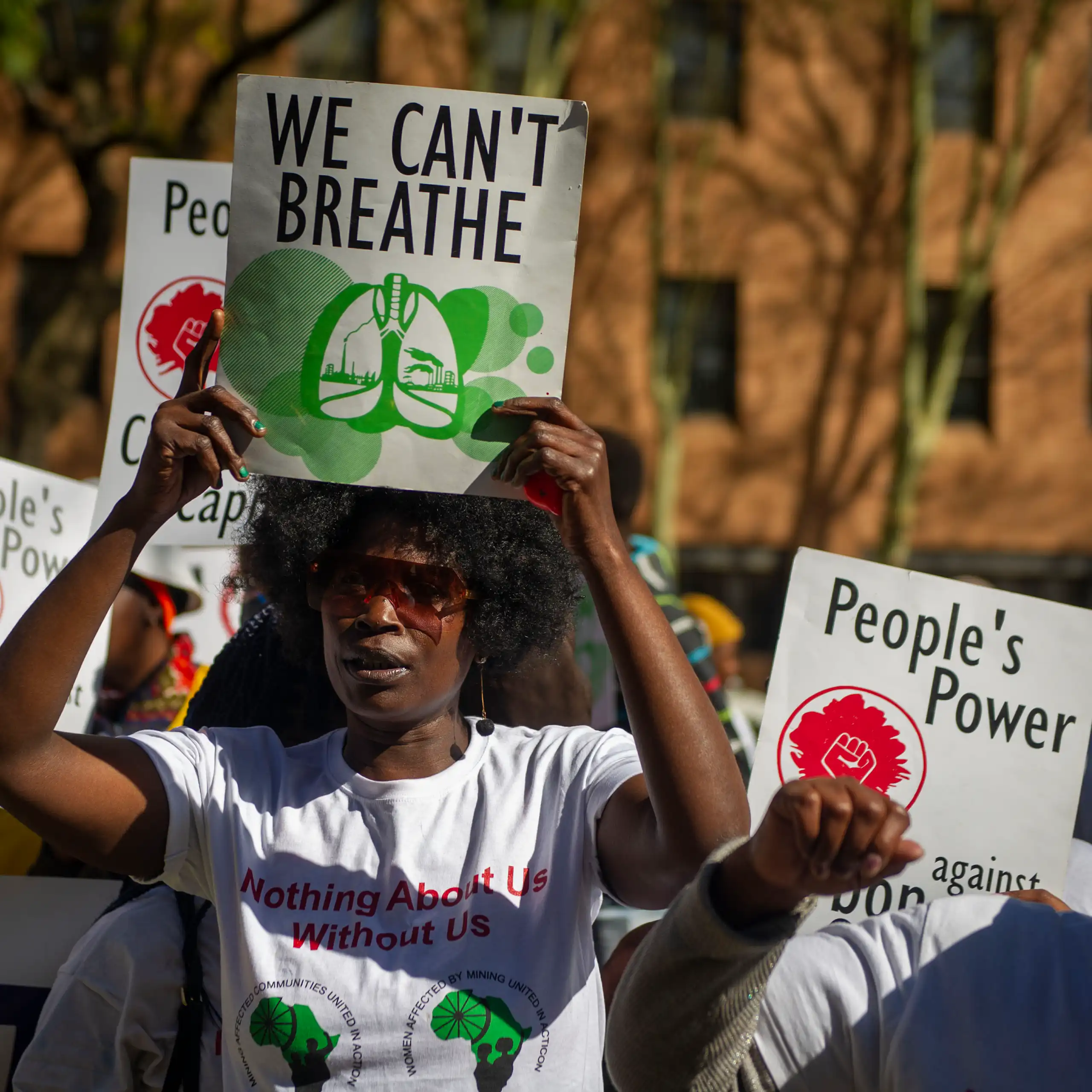 Students hold up signs saying 'People's power' and 'We Can't Breathe'