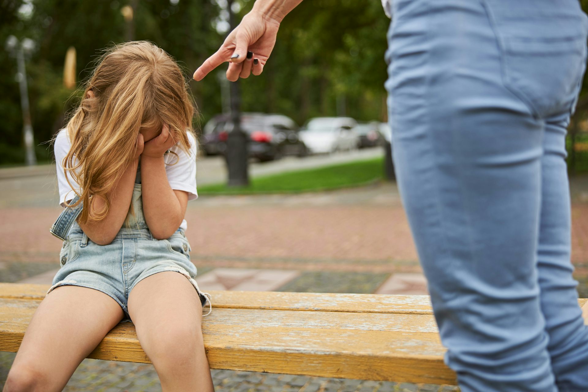 Une petite fille cache son visage dans ses mains tandis que sa mère la réprimande