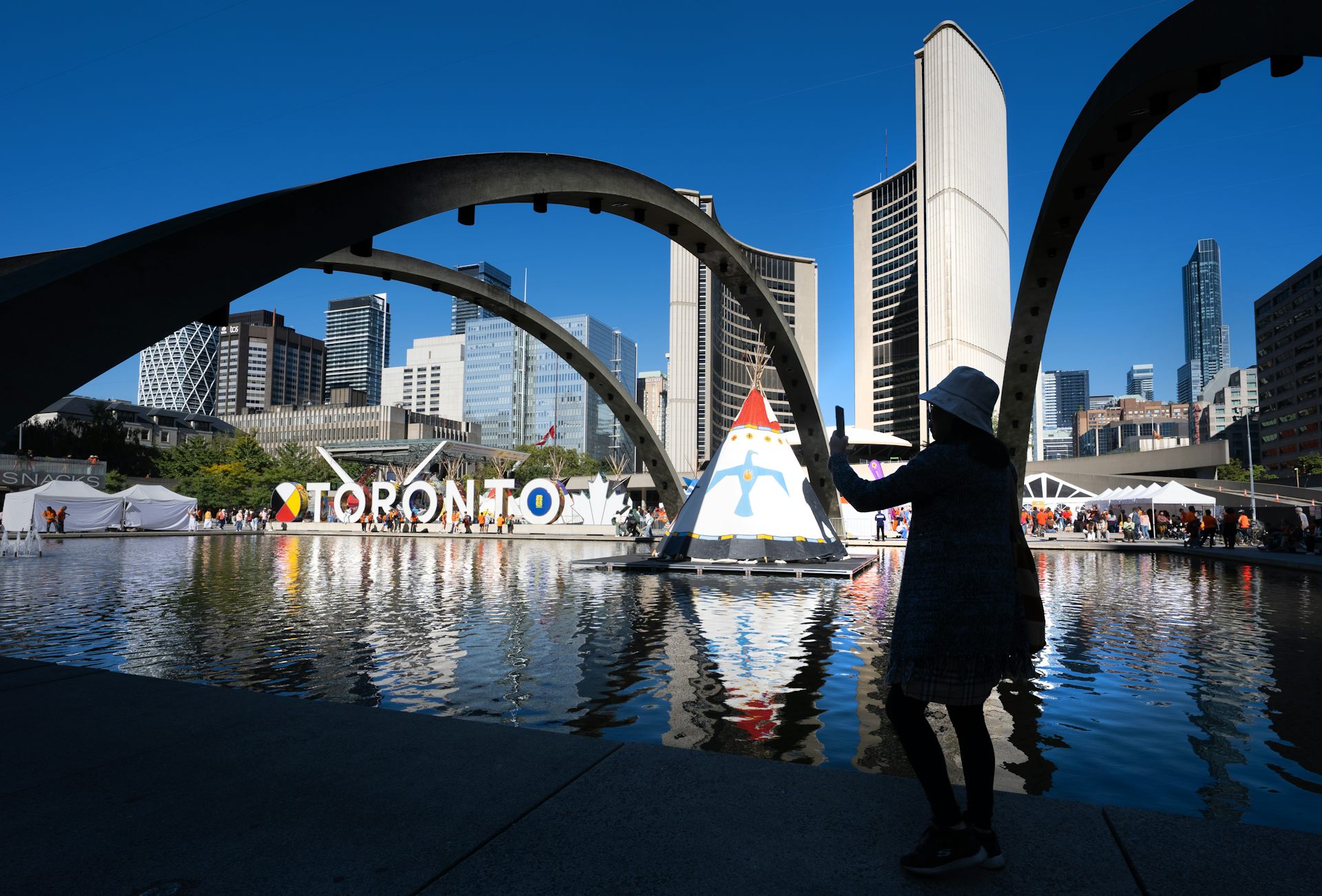 Una silueta de mujer toma una fotografía en el Ayuntamiento de Toronto.