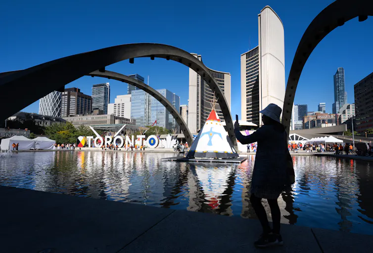 Una silueta de mujer toma una fotografía en el Ayuntamiento de Toronto.
