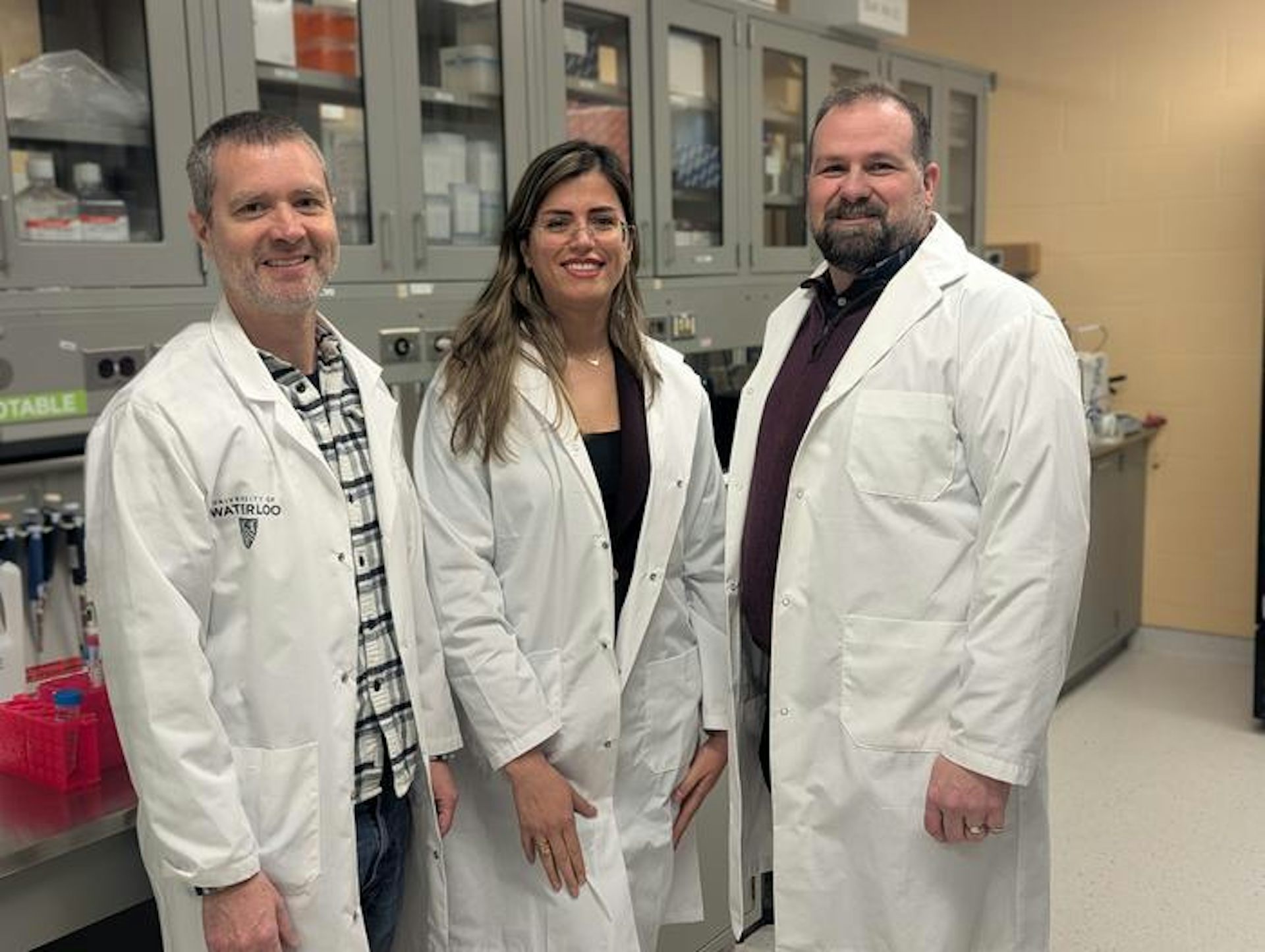Dos hombres y una mujer con batas blancas de laboratorio posan para una foto.