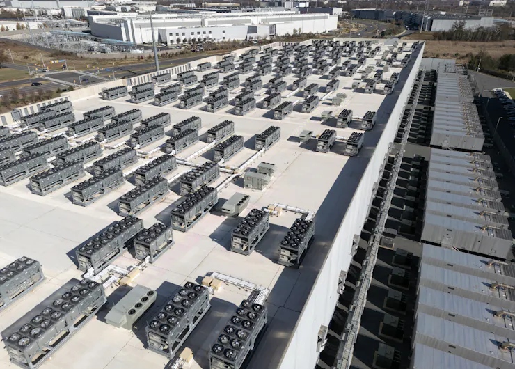 Rows of small equipment boxes sit atop the roof of a commercial building.