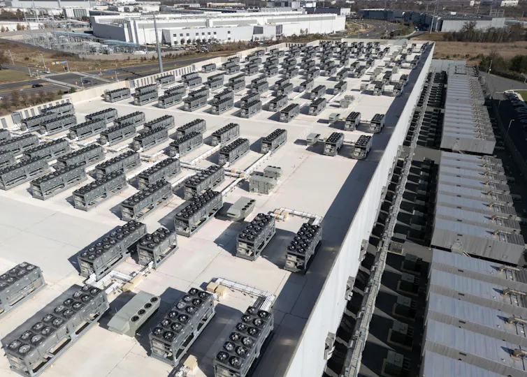 Rows of small equipment boxes sit atop the roof of a commercial building.