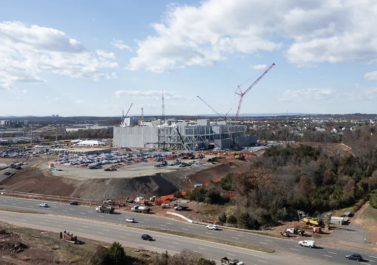 A construction site with many trucks and several cranes.