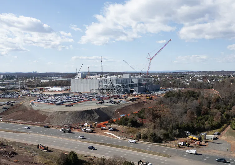 A construction site with many trucks and several cranes.