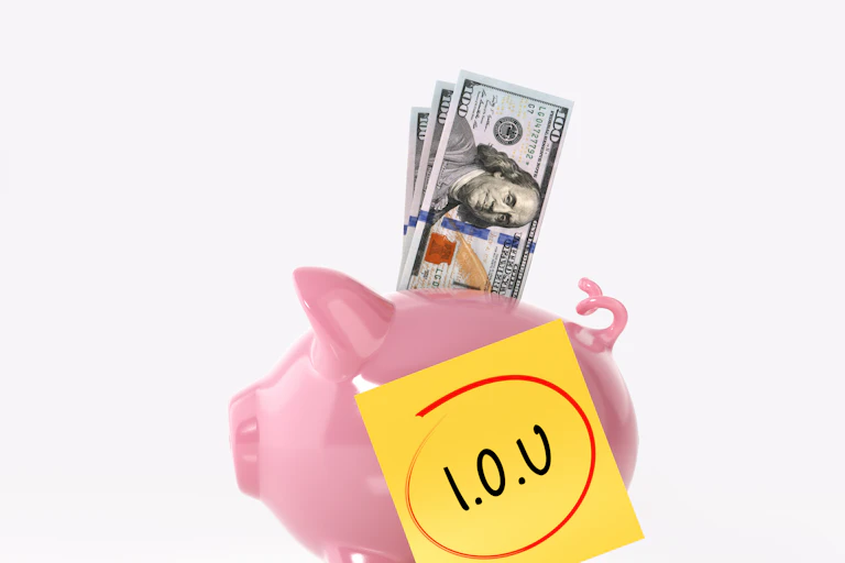 A piggy bank stuffed with U.S. $20 bills has a post-it note stuck on the side that says IOU.