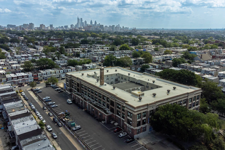Aerial view of large rectangular building surrounded by residential area with skyscrapers in background