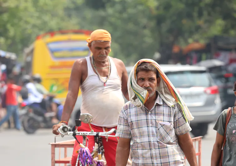 two men walking on Indian street, intense heat.