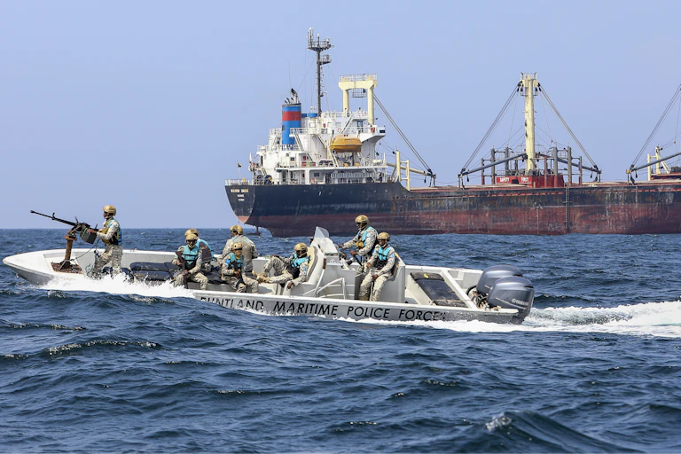 A group of the maritime policemen patrol Somalia's Puntland coast as a container ship sails by.