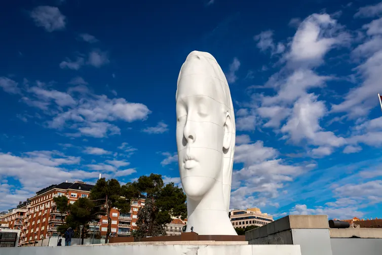 Fotografía de una escultura de una cabeza de mujer gigante, casi plana por los lados.