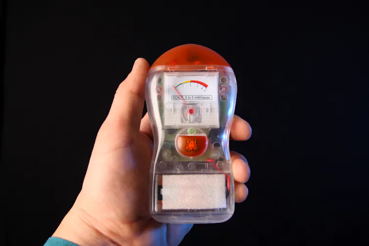 hand holds a tech device with a meter readout at the top