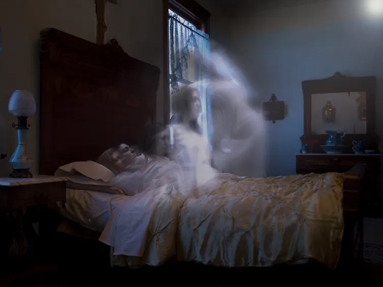 woman lying in bed with transparent image of woman rising away from her reclined body