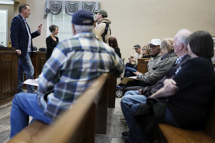 People engage at a meeting, where many of them appear to be over 65.