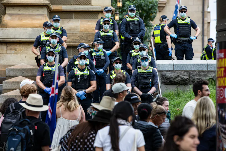 Members of Victoria Police stand in front of anti-vaccination protesters in Melbourne, 2022.