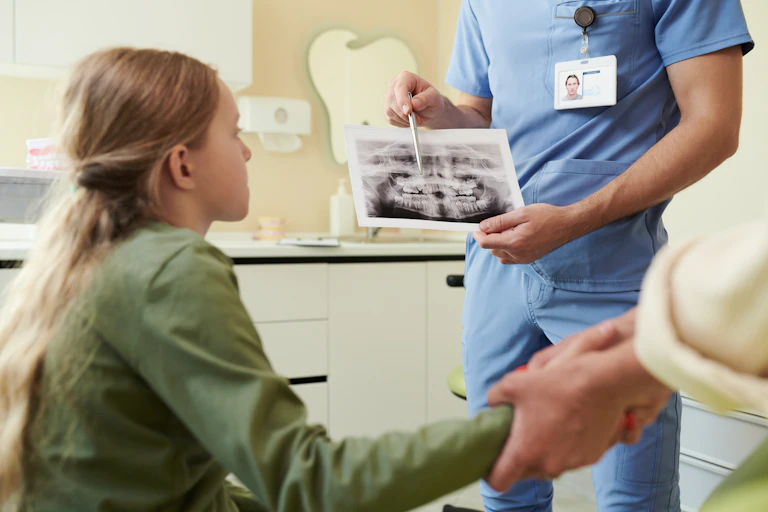 Un dentista le enseña una radiografía a una niña