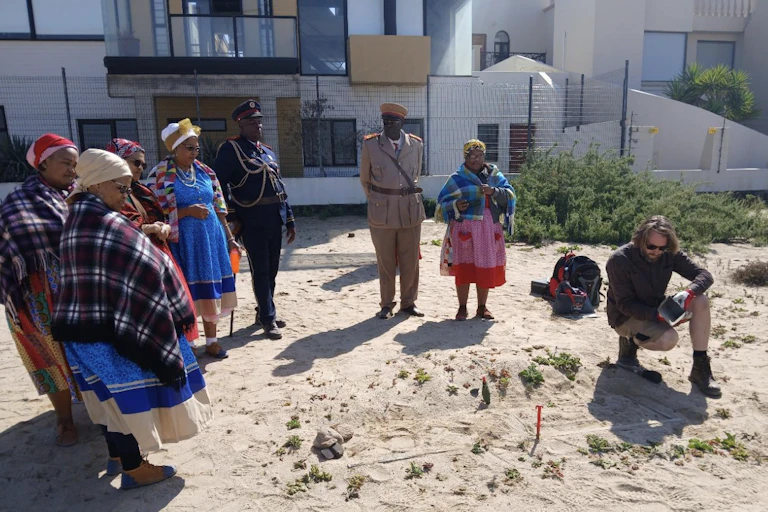 People standing looking at an exposed coffin sticking out of the earth