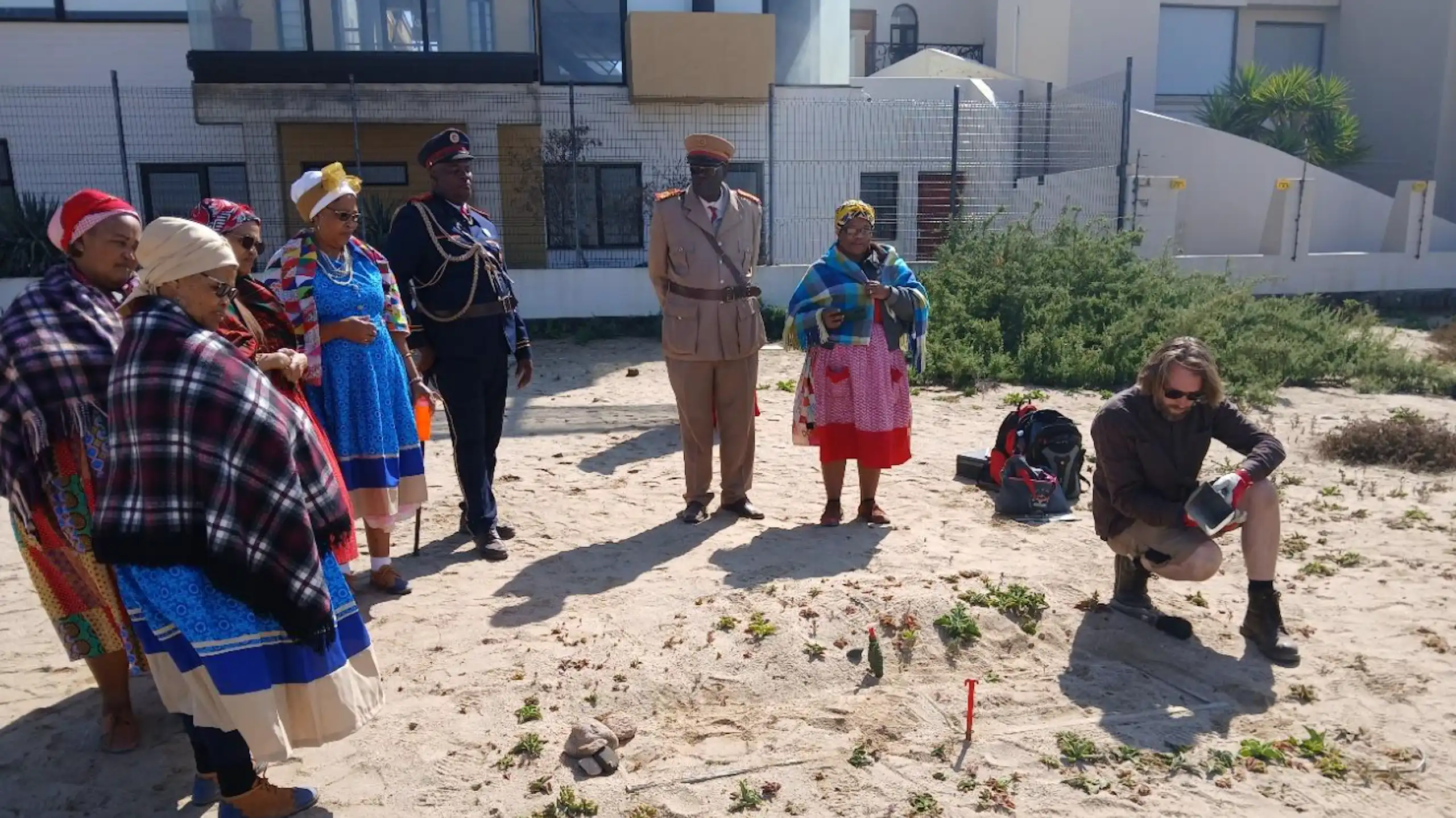 People standing looking at an exposed coffin sticking out of the earth