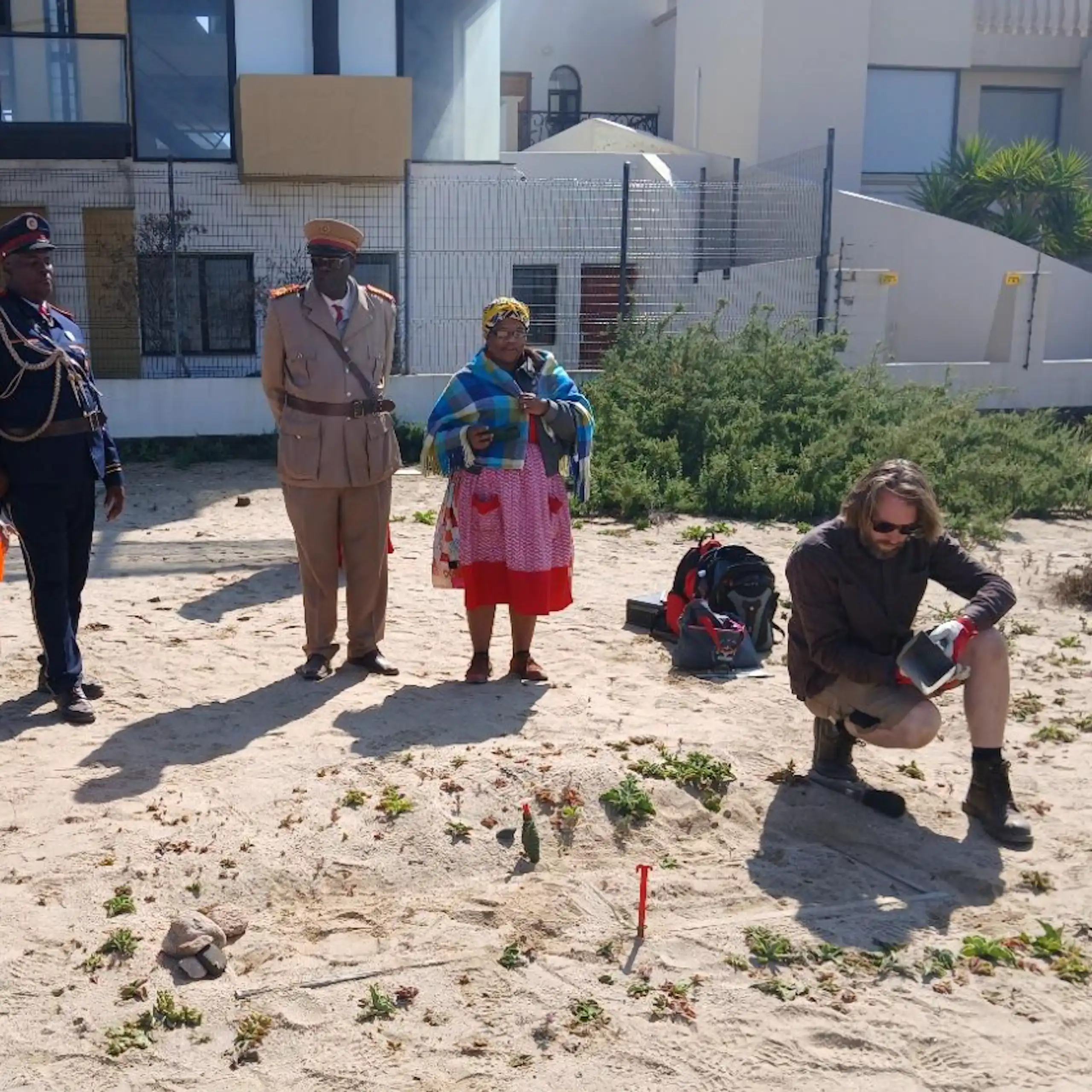 People standing looking at an exposed coffin sticking out of the earth