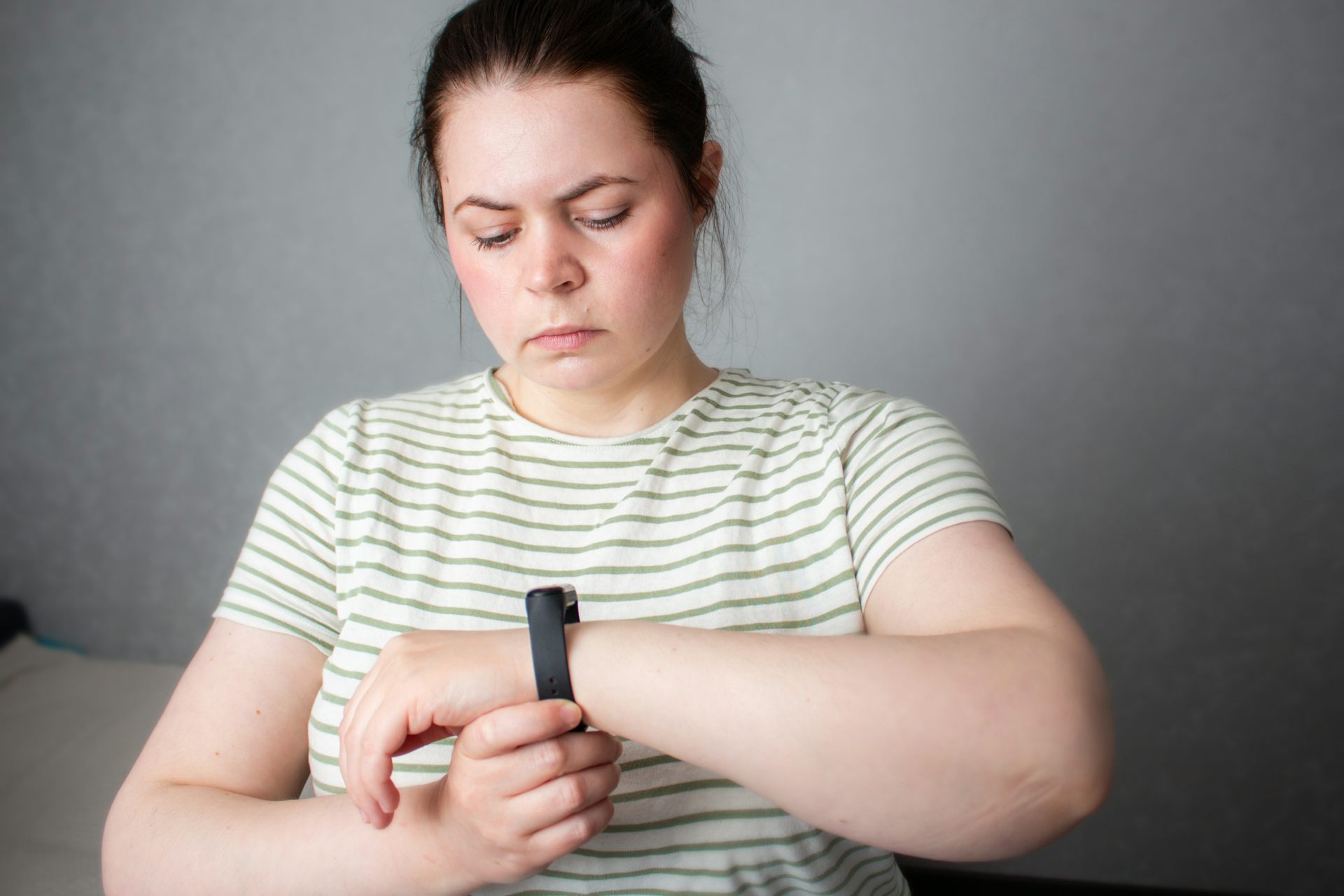 A woman looks in concern at the smartwatch on her wrist,