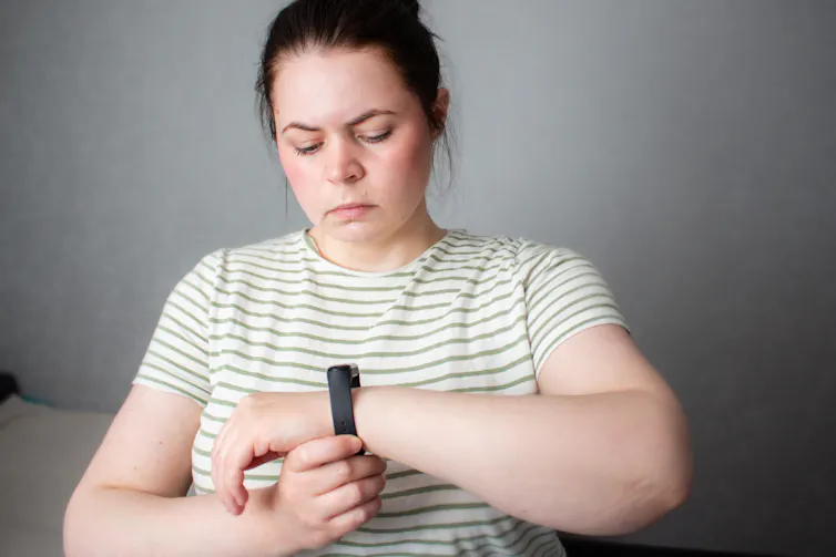 A woman looks in concern at the smartwatch on her wrist,