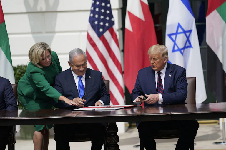 Israeli prime minister, Benjamin Netanyahu, and US president, Donald Trump, sit in front of the White House signing a document.