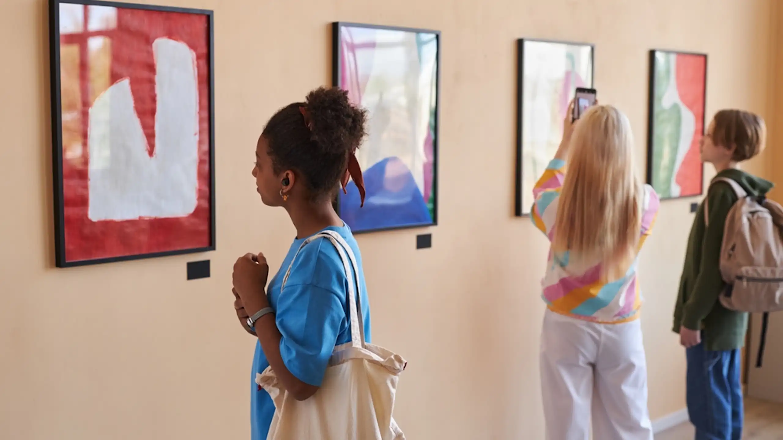 Des adolescents regardent des tableaux exposés dans une galerie.