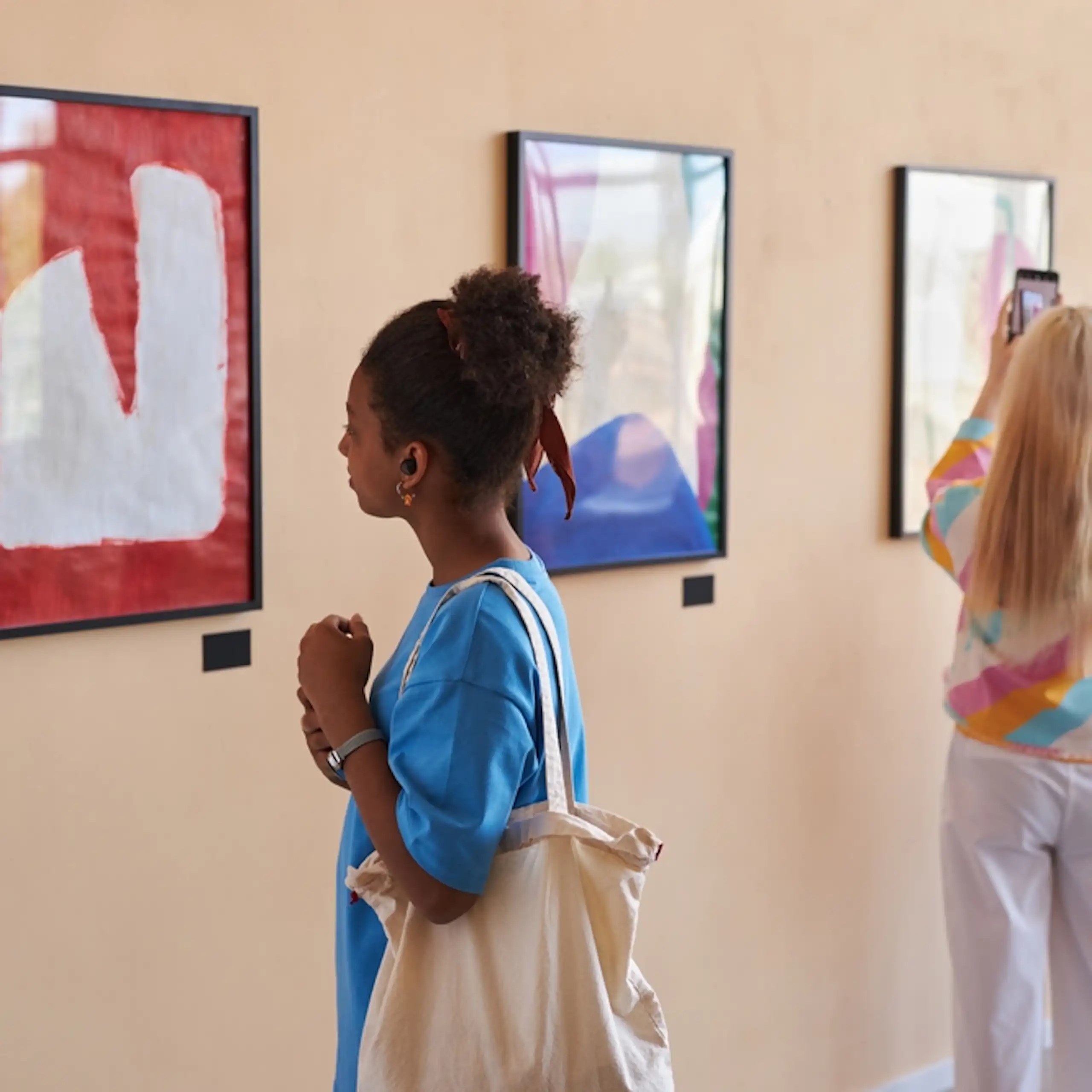 Des adolescents regardent des tableaux exposés dans une galerie.