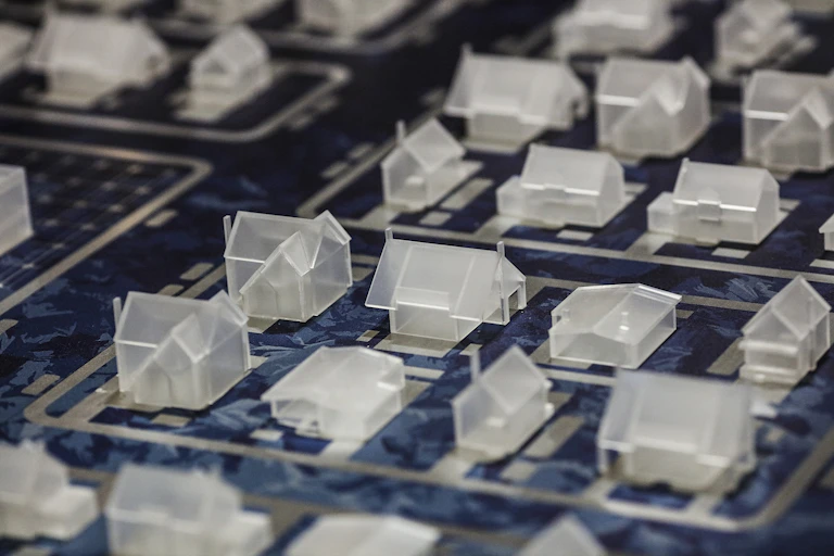 Miniature, clear plastic houses laid out side by side in a model of a neighborhood.