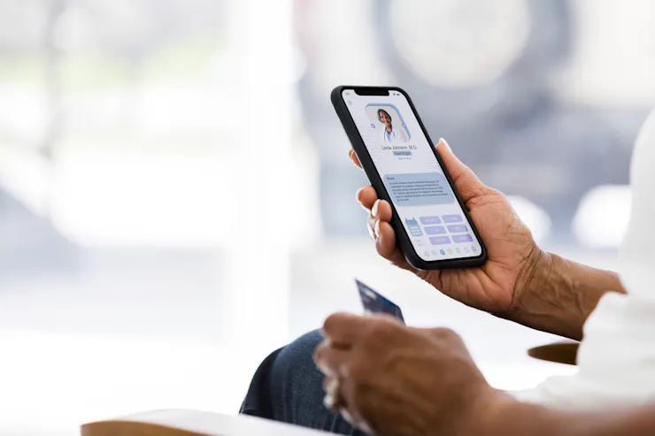 A person holds a phone screen that shows a text bubble and an image of a person in a white lab coat.