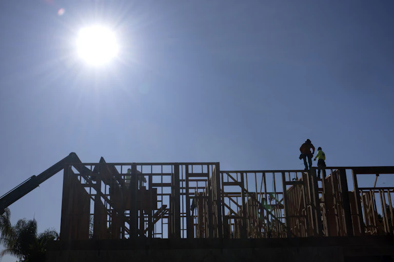 Construction workers work under the bright sun on a roof of a residential home in Los Angeles, Calif., on July 8, 2025.