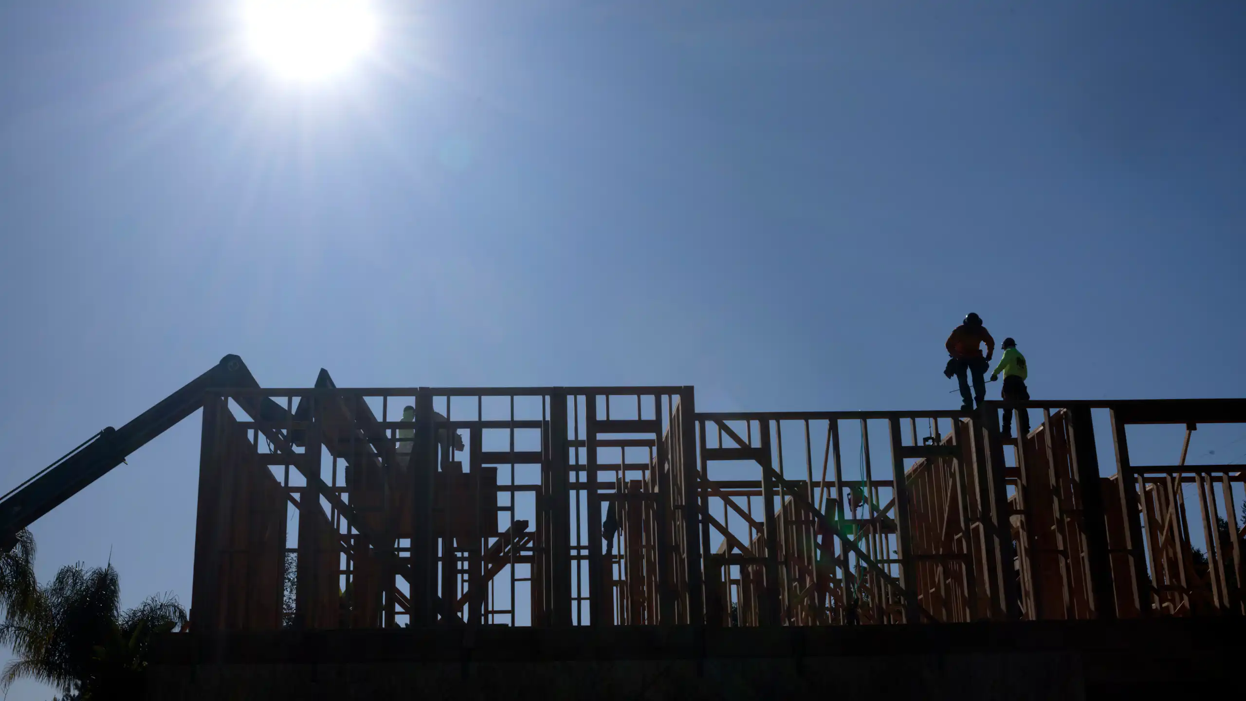 Construction workers work under the bright sun on a roof of a residential home in Los Angeles, Calif., on July 8, 2025.