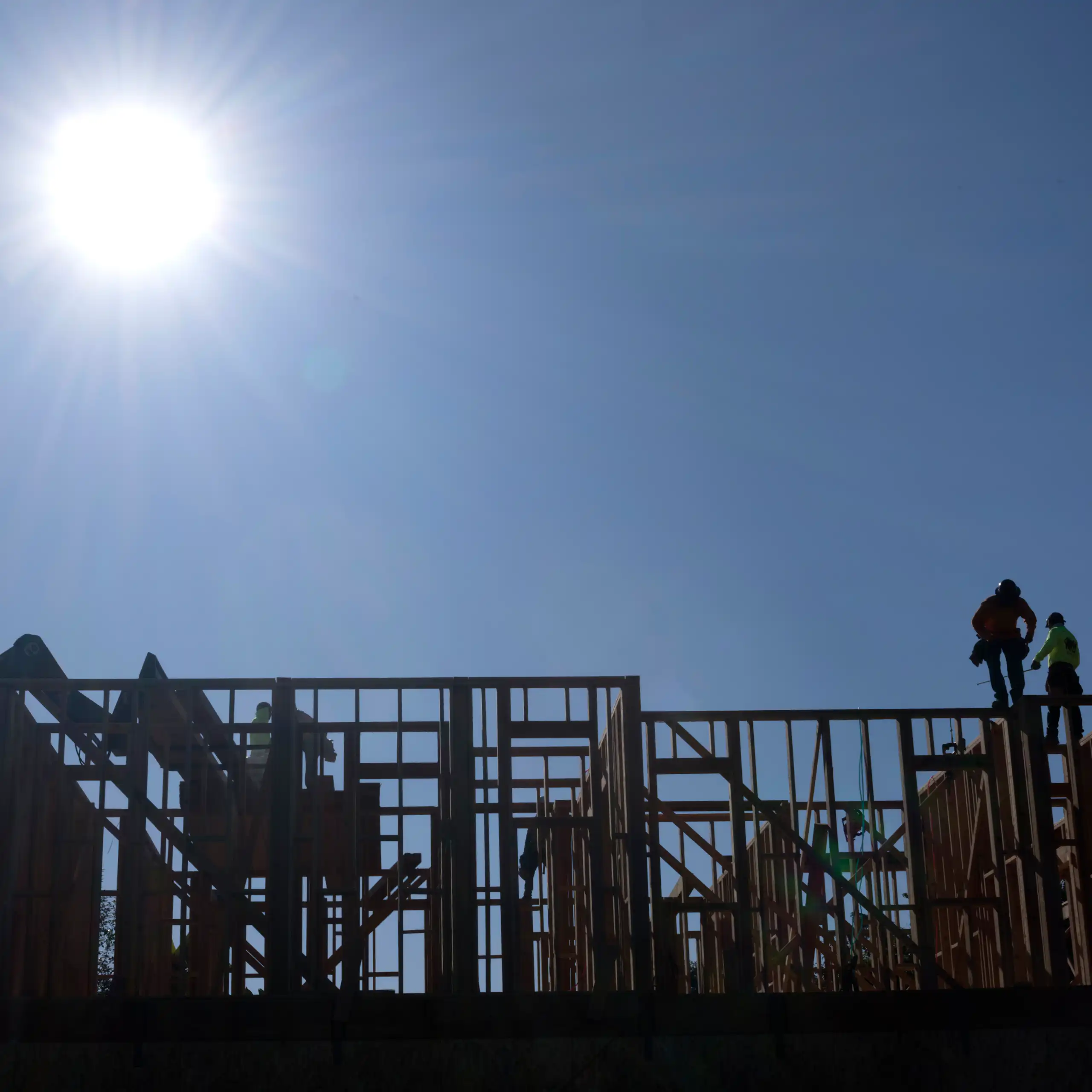 Construction workers work under the bright sun on a roof of a residential home in Los Angeles, Calif., on July 8, 2025.