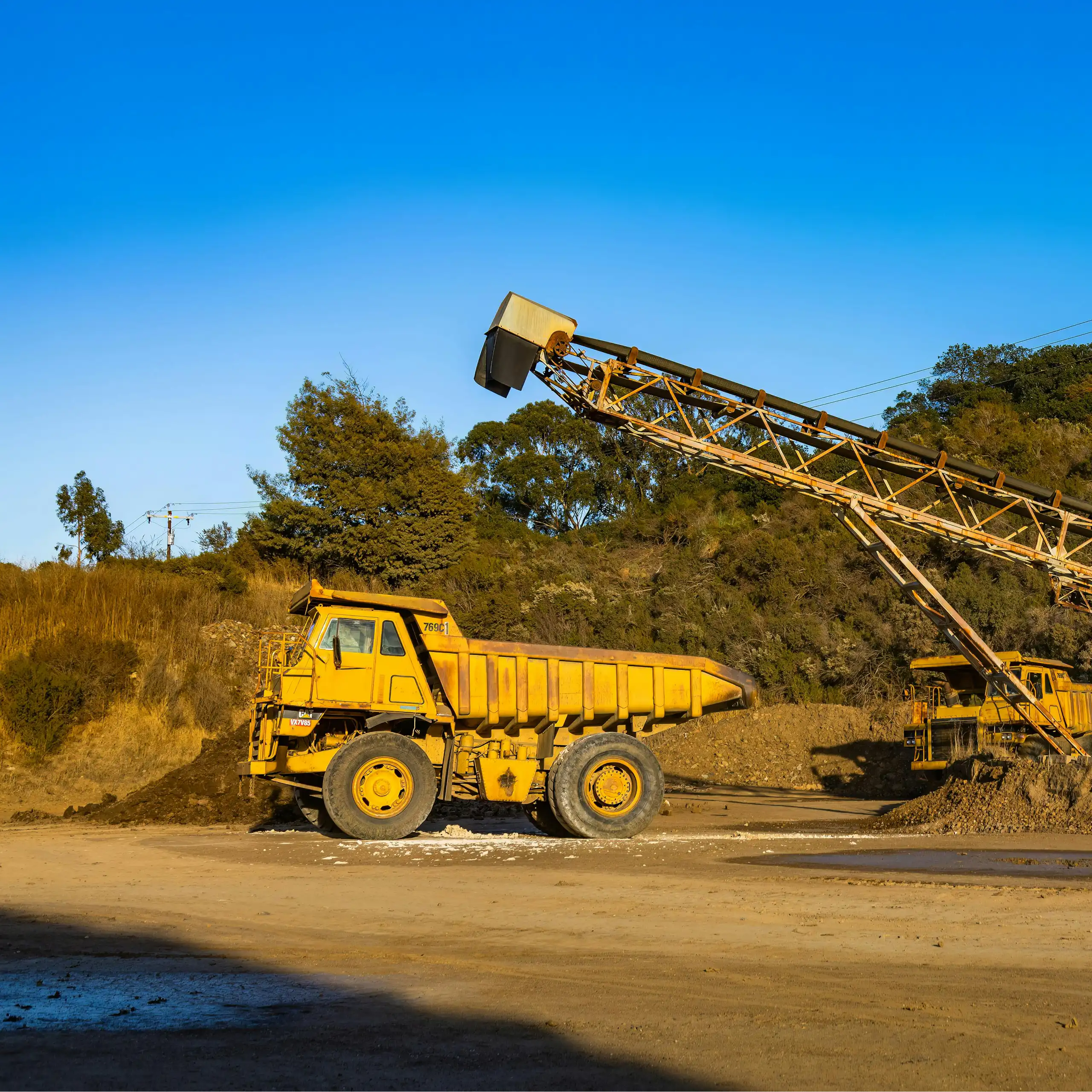 A big bulldozer and truck next to a lagoon