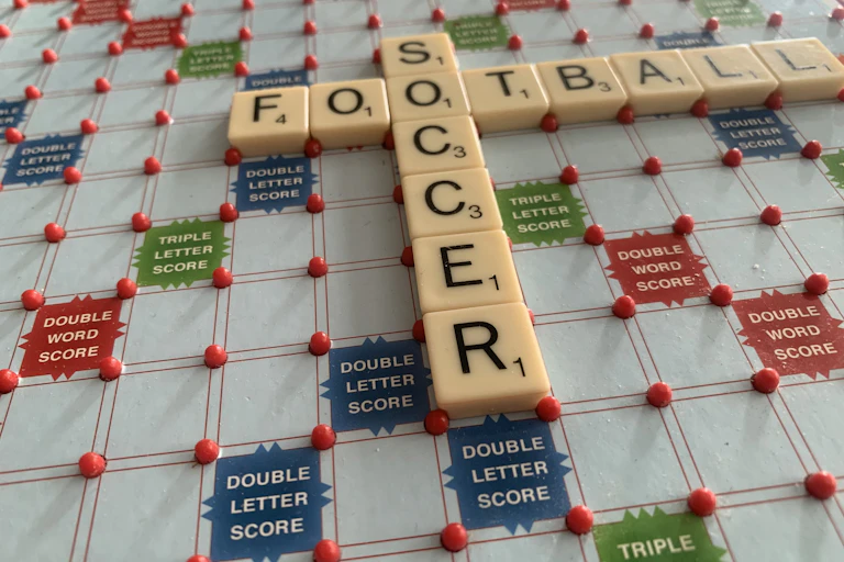 A scrabble board shows the words 'soccer' and 'football'