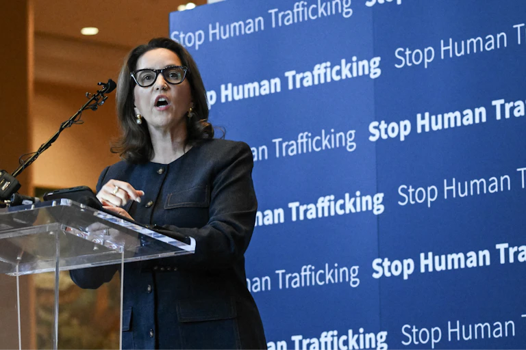 A woman stands at a platform in front of a display saying 'stop human trafficking.