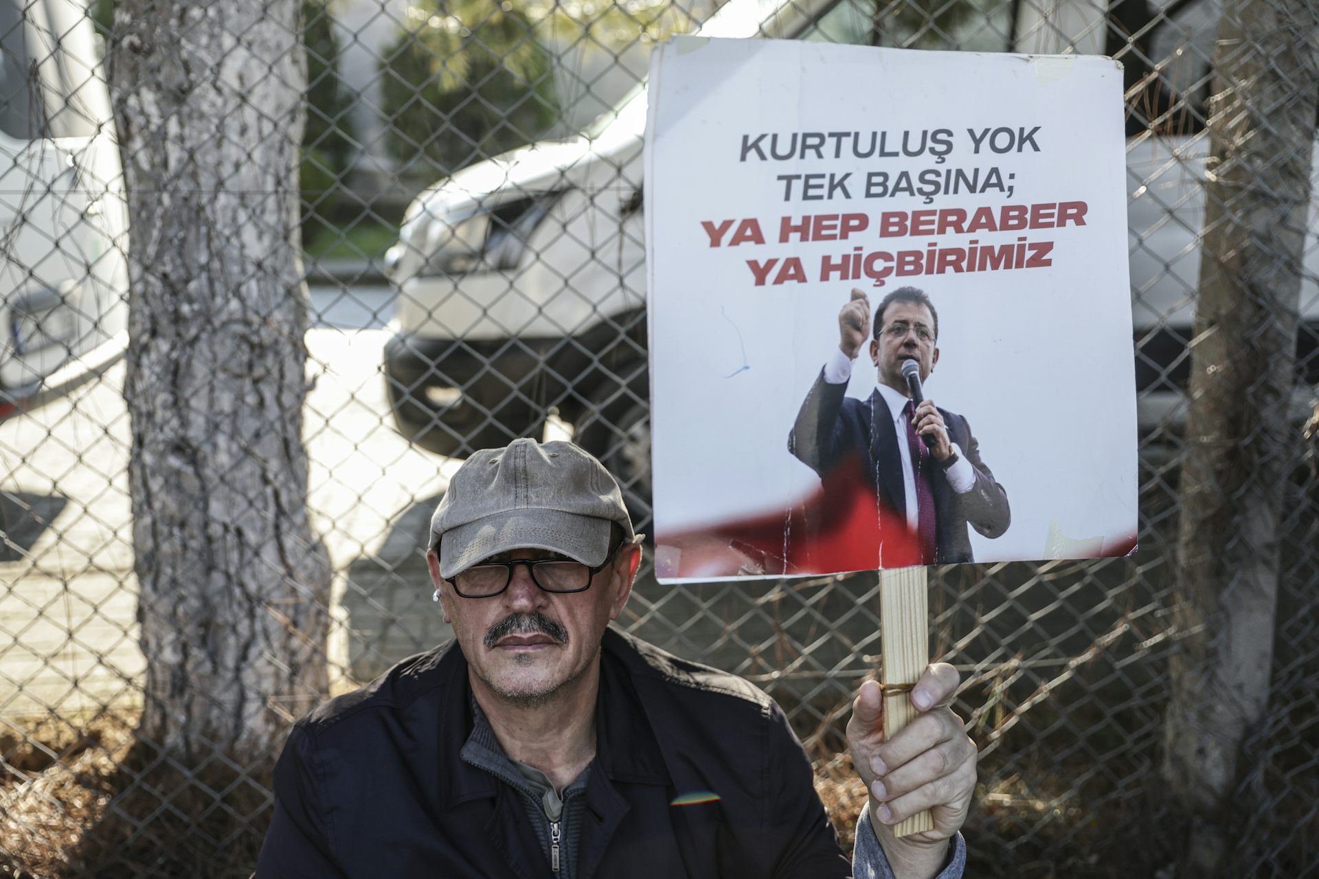 A supporter of jailed Istanbul mayor, Ekrem Imamoglu holds up a placard with a picture of  Imamoglu and the phrase: 'There is no salvation alone, either all together or none of us':