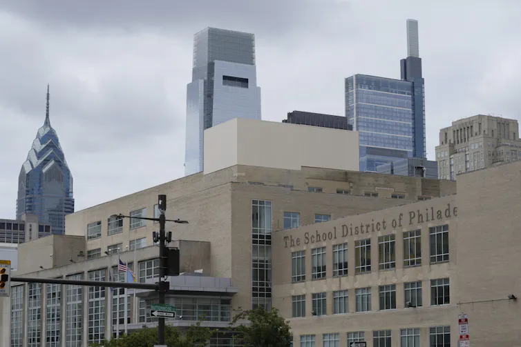 Shot of large beige building in foreground with glass skyscrapers in background