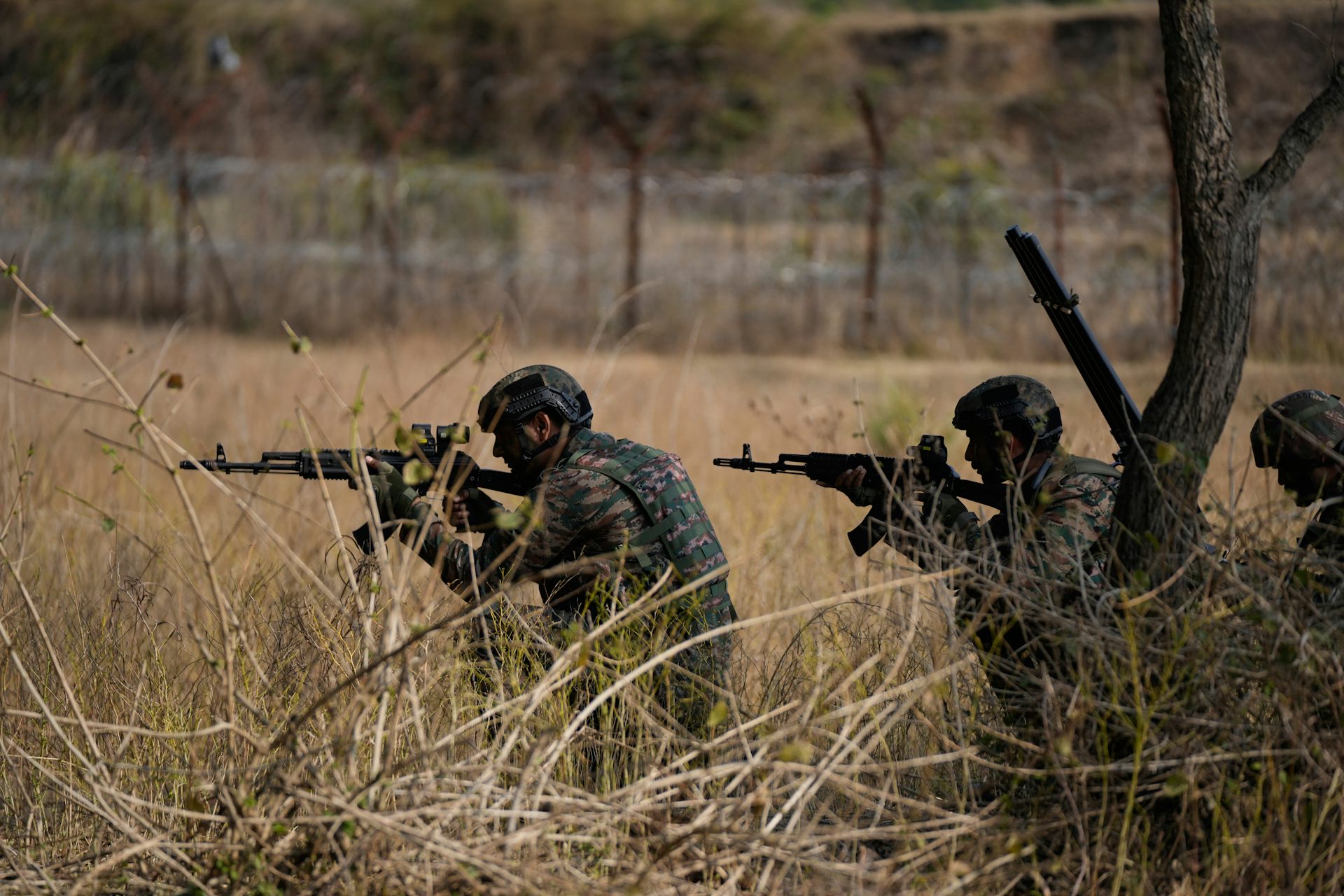 Soldiers in military fatigue holding guns.