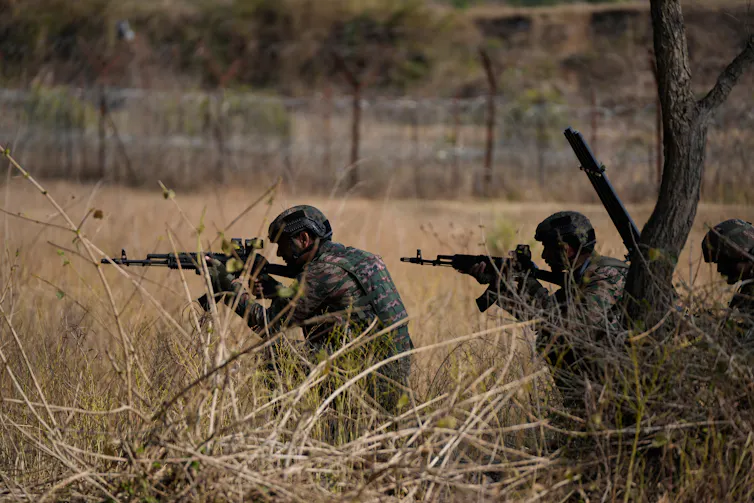 Soldiers in military fatigue holding guns.